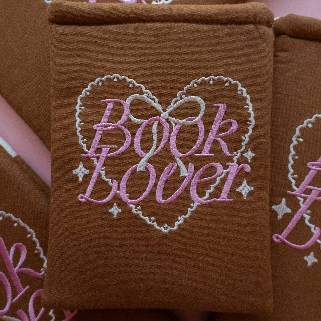 Brown fabric with 'Book Lover' embroidery design on a pink background