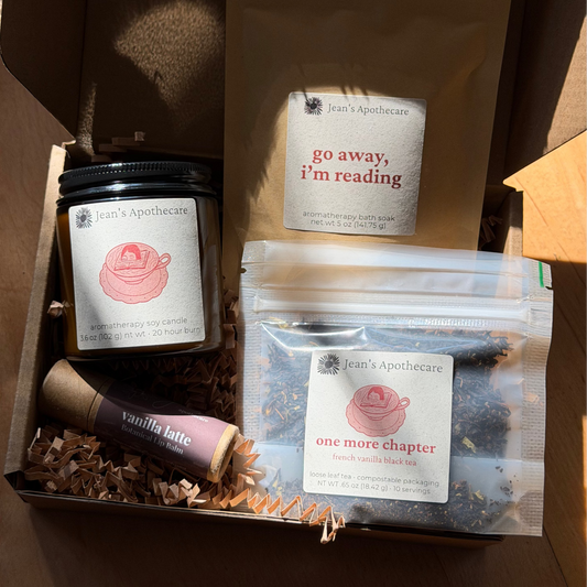 Box containing books, a candle, and a lip balm with visible branding.