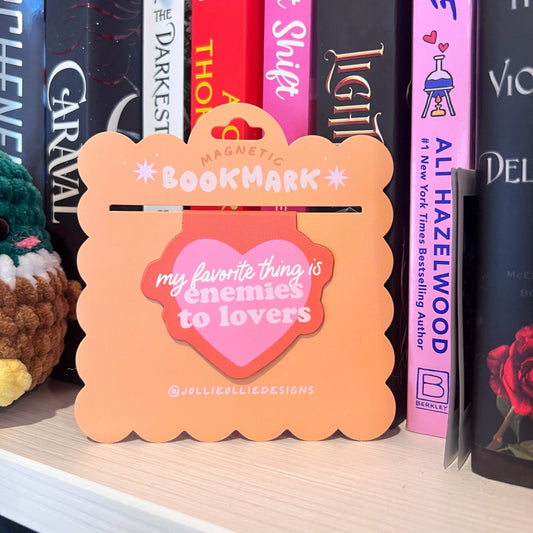 Orange magnetic bookmark with text on a bookshelf with books and a plush toy.