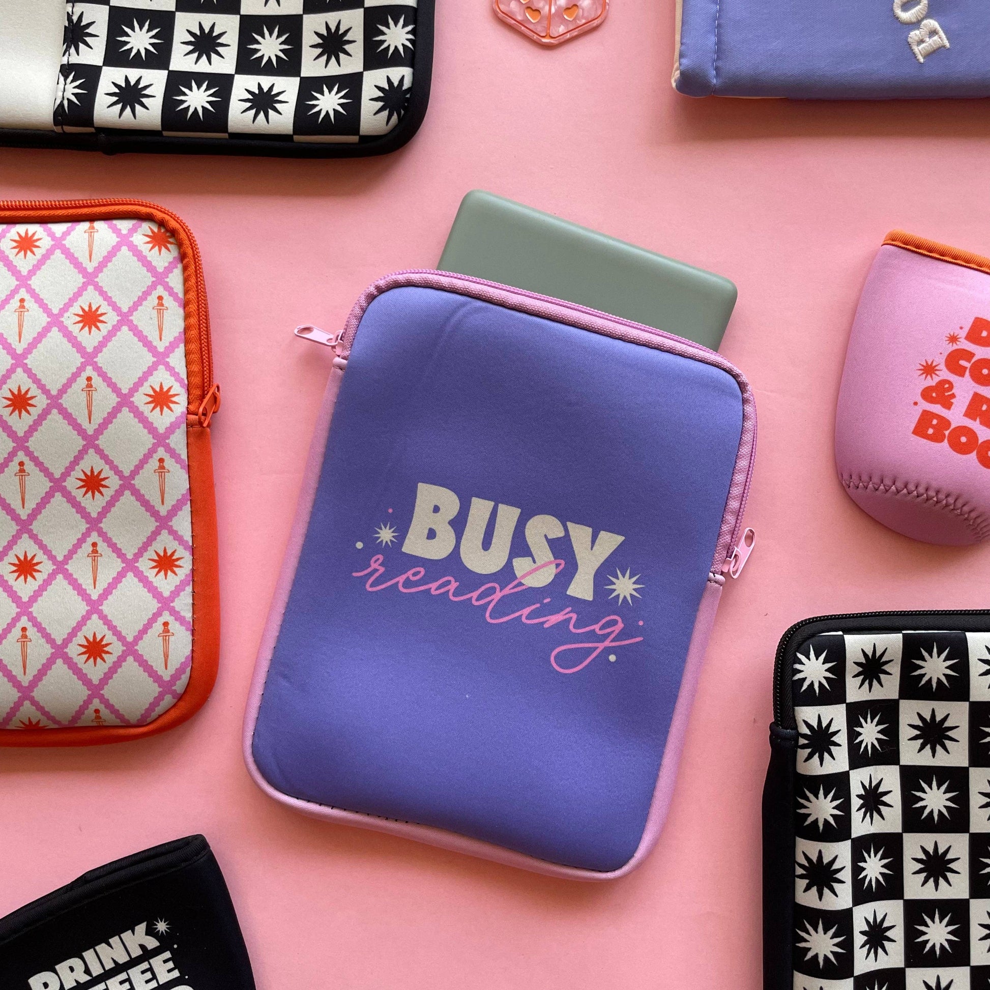 Collection of various pouches with different designs and text on a pink background