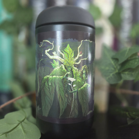 A black insulated tumbler with a matching lid, featuring a detailed graphic of a green mossy plant with glowing roots and a small white flower. The tumbler is photographed outdoors with blurred green leaves in the background.